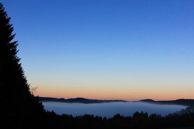 Scenic view of silhouette mountains against clear sky at sunset