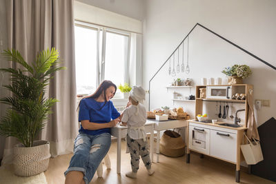 Rear view of woman standing by window