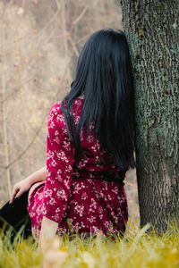 Midsection of woman on tree trunk