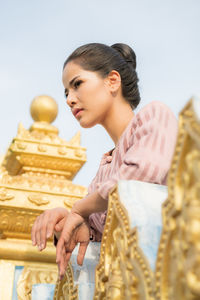 Low angle view of woman looking away while standing by railing