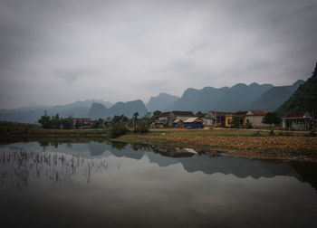 Scenic view of lake by buildings against sky