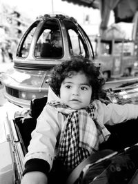 Baby boy looking away while sitting in carousel car