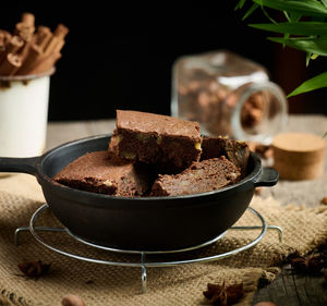 Pieces of baked brownie in a metal black frying pan on the table