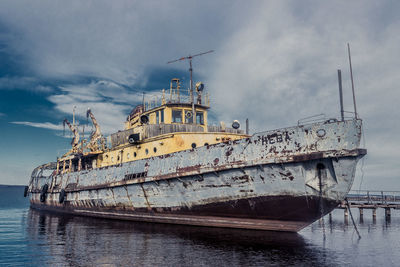 Abandoned ship amidst sea against sky