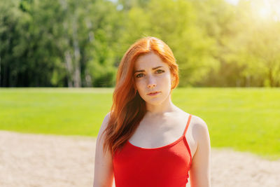 Portrait of young woman standing against trees