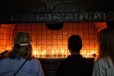 Rear view of people standing against illuminated wall