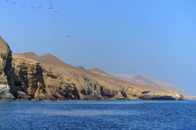 Scenic view of sea and mountains against clear blue sky