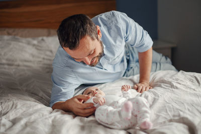 Proud caucasian father playing with newborn baby girl. smiling man parent talking to child 