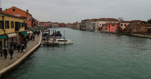 Boats in canal amidst buildings in city against sky