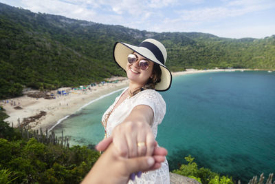 Couple holding hands on mountain by sea