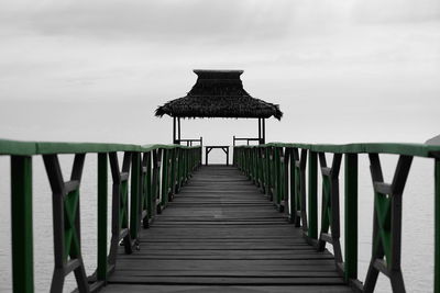 Empty wooden pier on sea against sky