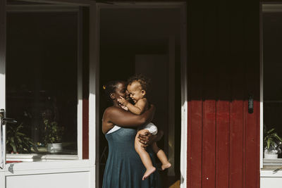 Mother with toddler in front of house