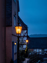 Illuminated street light against building at night