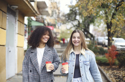 Smiling friends standing against trees