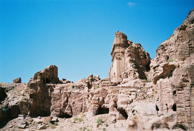 Low angle view of cliff against blue sky