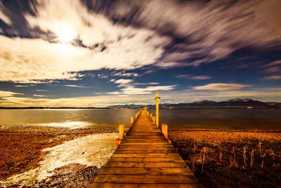 Pier over sea against sky during sunset