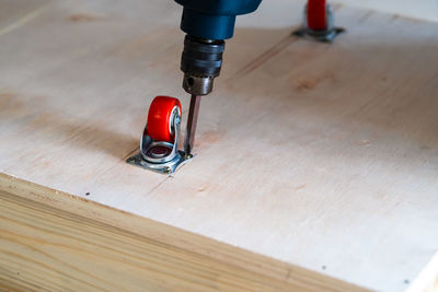 High angle view of castor wheels and electrical drill on table.