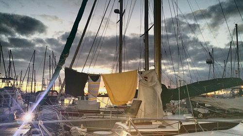 Boats moored at harbor against cloudy sky