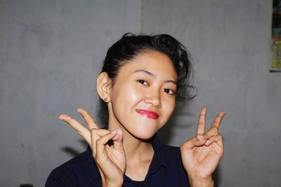 Portrait of smiling young woman against wall