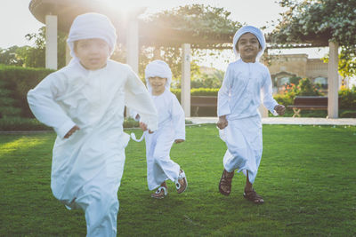 Brothers wearing traditional clothing running on grassy land in park