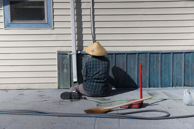 Rear view of woman sitting by window against building