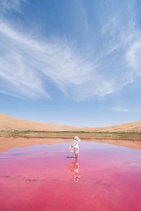 Woman standing in lake against sky