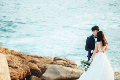 Young couple kissing against sea