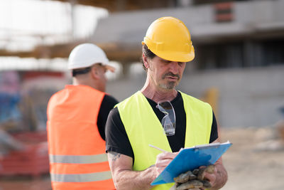 Architect writing in clipboard at construction site