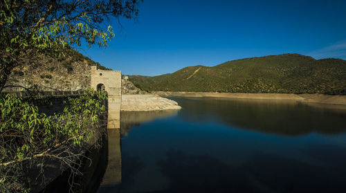 Scenic view of lake and mountains against clear blue sky