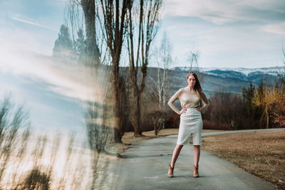 Full length of woman standing on road against sky