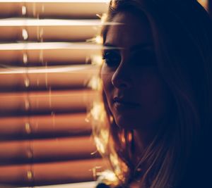 Close-up of woman against blinds at home