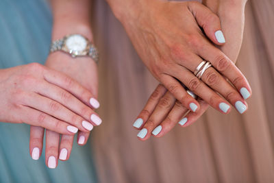 Close-up of women showing their nail polishes on fingernails