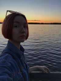 Portrait of young woman in lake against sky during sunset