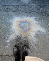 Low section of woman standing by spilled oil on road