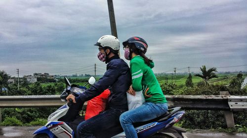 Woman standing on railroad track against cloudy sky