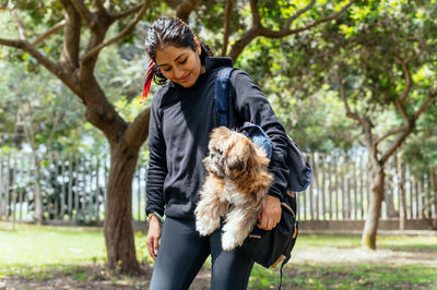 Side view of young woman with dog on field