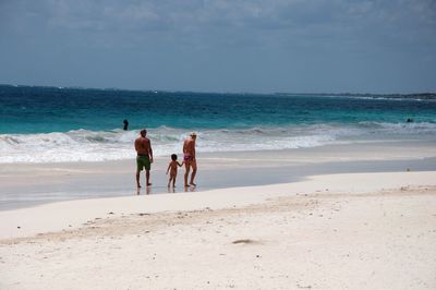 Rear view of people on beach against sky