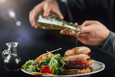 Chef pouring olive oil onto a vegan burger