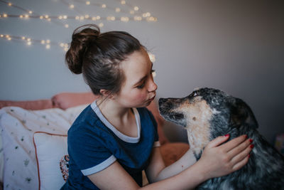 Tween girl playing with dog on her bed