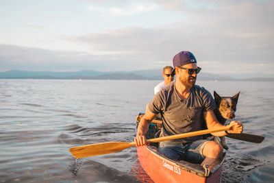 Man sitting on boat in sea against sky