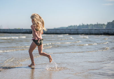 Rear view of girl running on beach