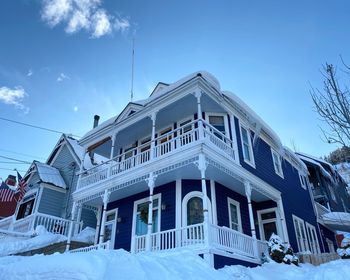 Low angle view of snow covered building against blue sky