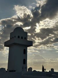 Lighthouse by sea against sky during sunset