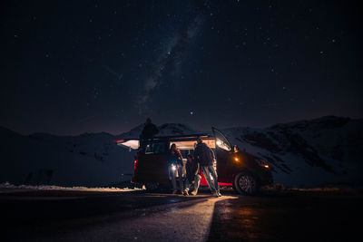 Illuminated road by mountain against sky at night