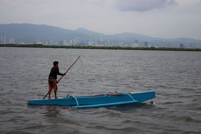 Rear view of man surfing in sea against sky