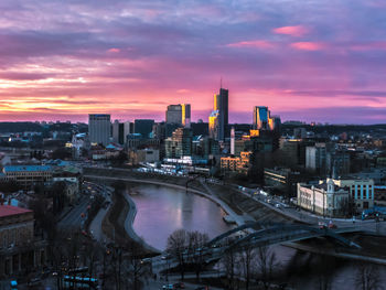 Illuminated buildings in city against sky at sunset