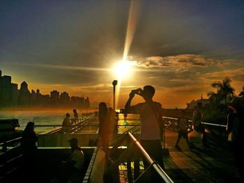 Silhouette people at beach against sky during sunset