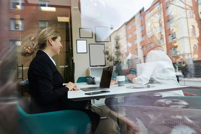 Smiling real estate agent looking at elderly couple talking in office