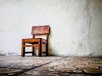 Empty chairs and table against wall
