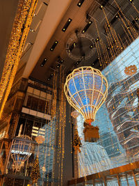 Low angle view of illuminated chandelier hanging in shopping mall